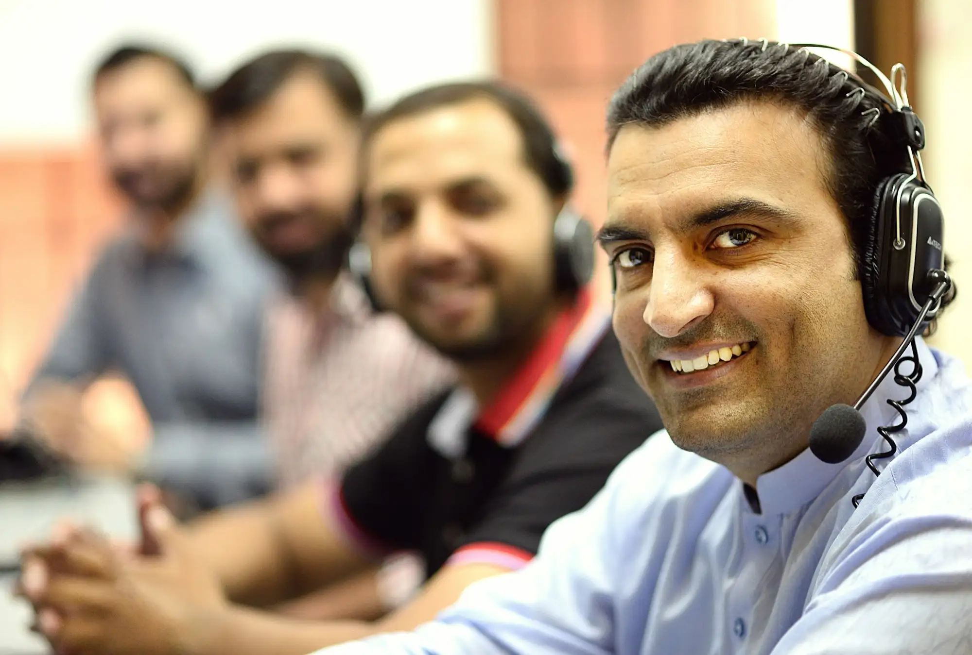 Smiling man wearing a headset while he helps a customer