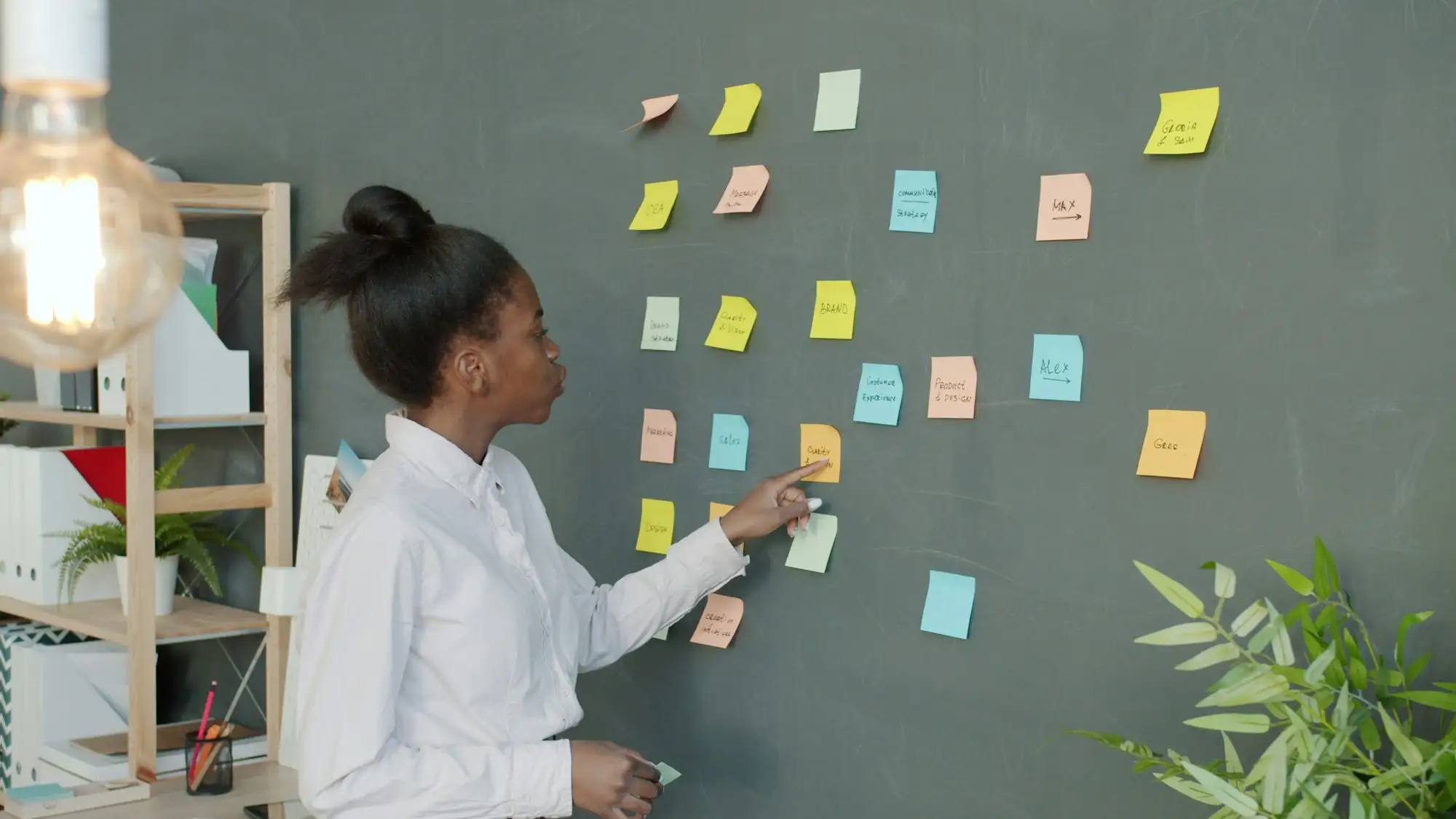 Woman pointing at colorful sticky notes on a wall during a planning session